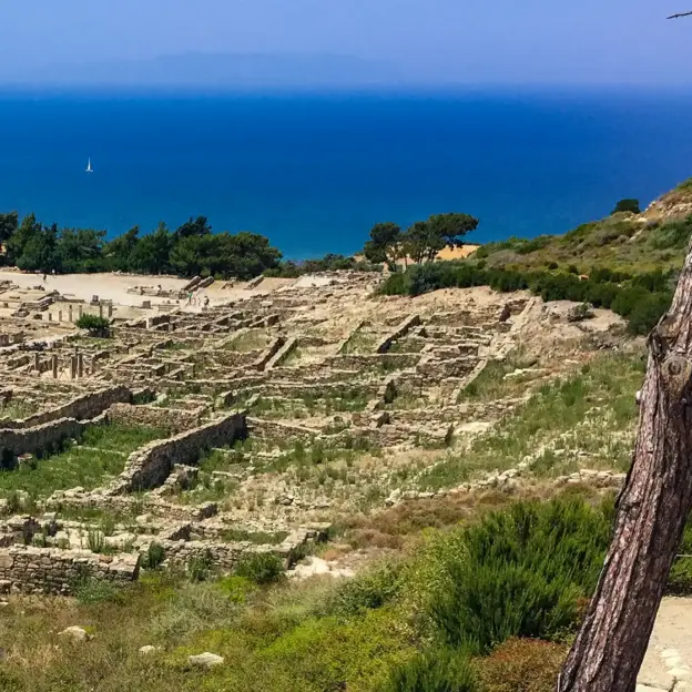 Antike Steinruinen in Kamiros mit Blick auf das blaue Meer und einem Segelboot in der Ferne.
